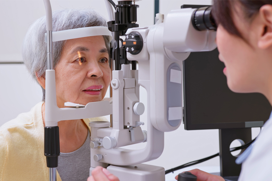 A patient receives an eye exam using specialized equipment while a healthcare professional evaluates her eyes.
