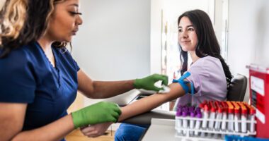 young woman smiles while getting blood drawn