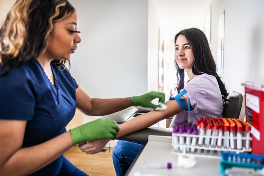 young woman smiles while getting blood drawn